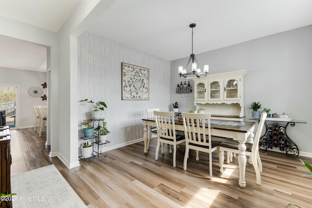 dining space with a notable chandelier and light hardwood / wood-style flooring