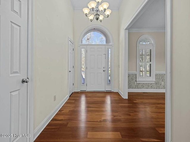 foyer with an inviting chandelier, dark hardwood / wood-style flooring, and ornamental molding