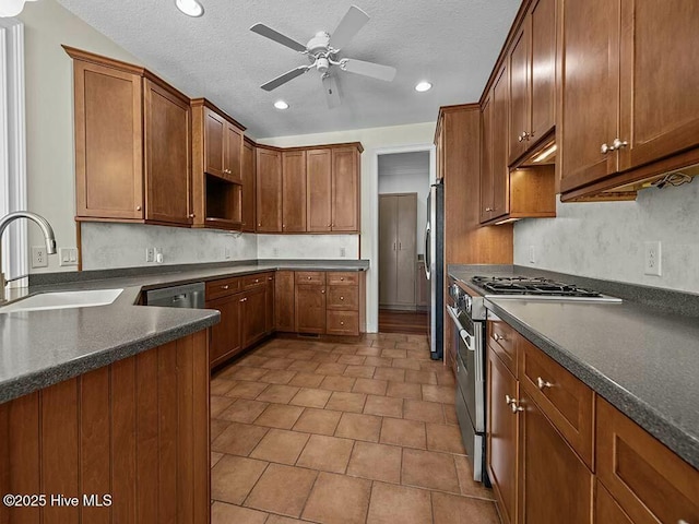 kitchen featuring stainless steel appliances, ceiling fan, sink, and a textured ceiling