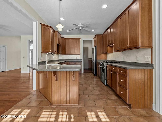 kitchen featuring sink, a breakfast bar, appliances with stainless steel finishes, decorative light fixtures, and kitchen peninsula