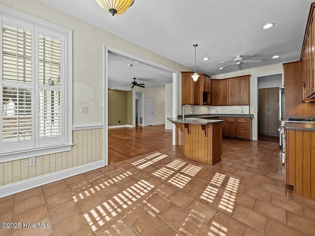 kitchen featuring hanging light fixtures, stainless steel range with gas cooktop, a healthy amount of sunlight, and a breakfast bar