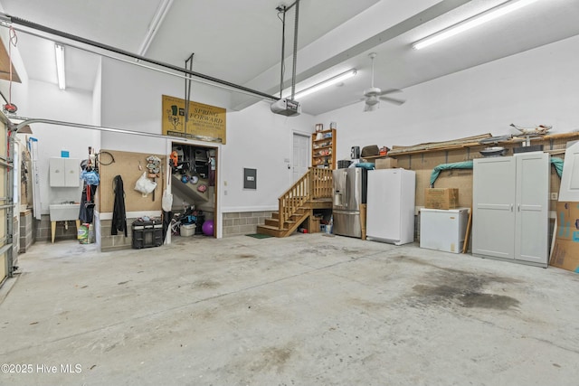 garage featuring stainless steel fridge, white refrigerator, fridge, electric panel, and a garage door opener