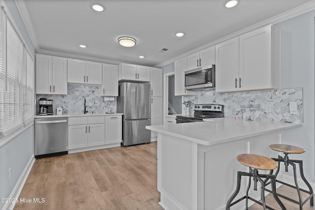 kitchen featuring stainless steel appliances, white cabinetry, sink, and kitchen peninsula