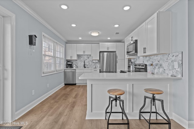 kitchen with sink, a breakfast bar area, white cabinetry, appliances with stainless steel finishes, and kitchen peninsula