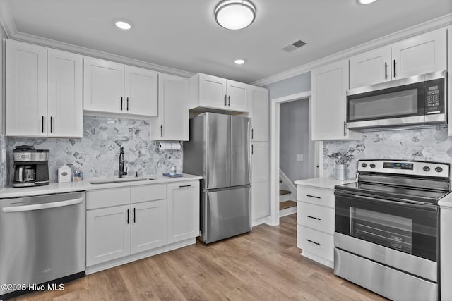 kitchen with white cabinetry, sink, stainless steel appliances, and light hardwood / wood-style floors