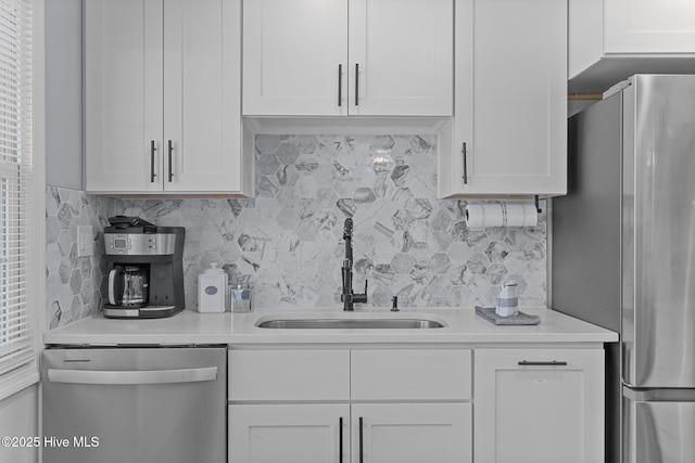 kitchen featuring sink, decorative backsplash, stainless steel appliances, and white cabinets