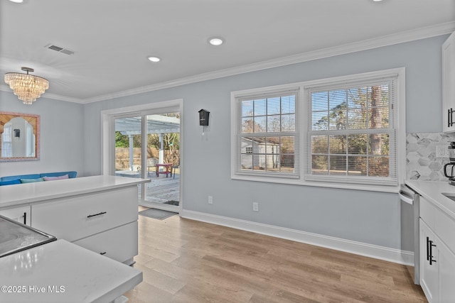 kitchen featuring crown molding, light hardwood / wood-style flooring, white cabinetry, decorative backsplash, and stainless steel dishwasher