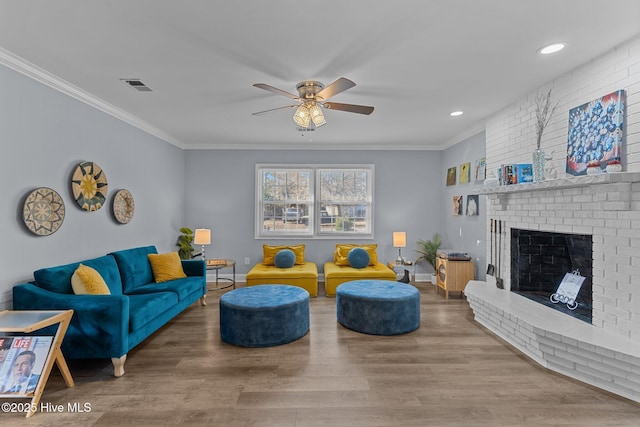 living room with ornamental molding, hardwood / wood-style floors, ceiling fan, and a fireplace