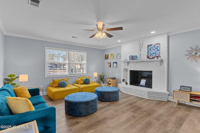 living room with crown molding, ceiling fan, a fireplace, and light hardwood / wood-style floors