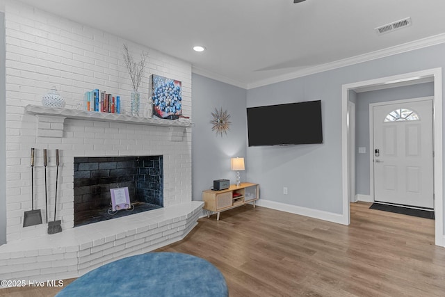 living room featuring ornamental molding, a brick fireplace, and hardwood / wood-style floors