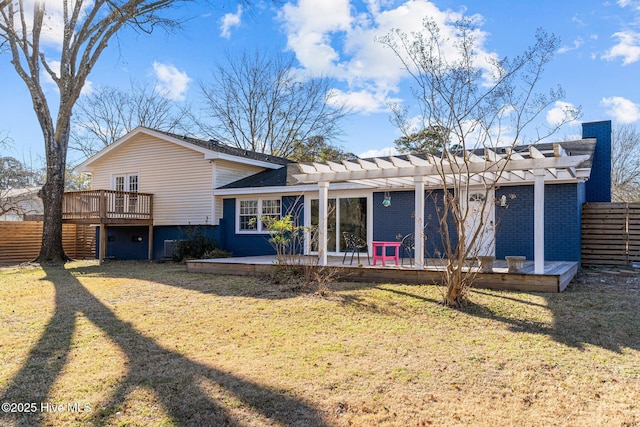 rear view of property featuring a yard, a pergola, and a deck