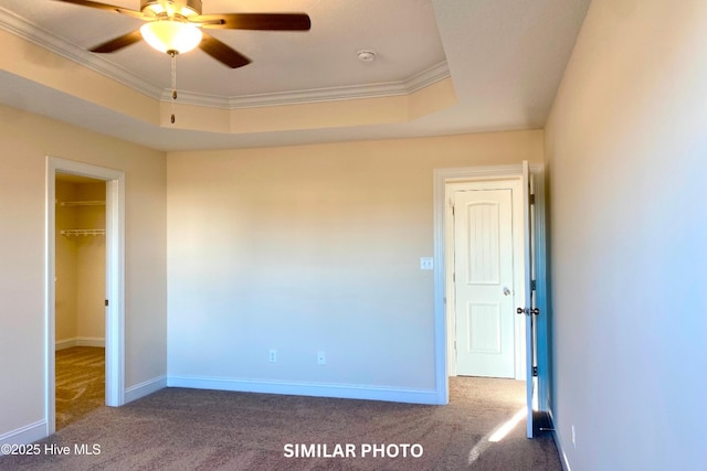 unfurnished bedroom featuring ceiling fan, a raised ceiling, carpet floors, and crown molding