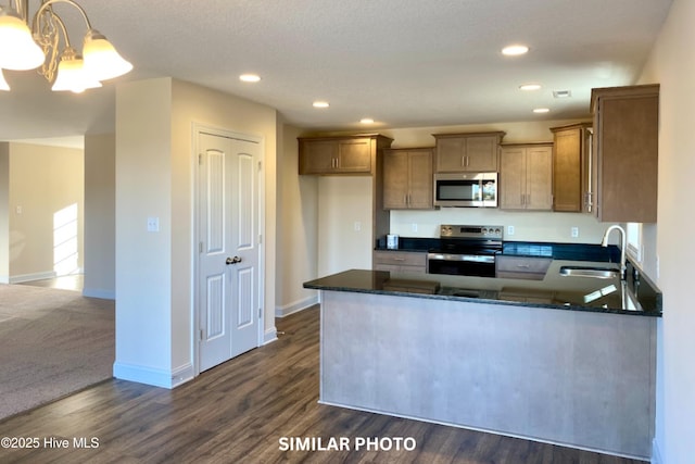 kitchen featuring sink, stainless steel appliances, dark hardwood / wood-style flooring, dark stone counters, and decorative light fixtures