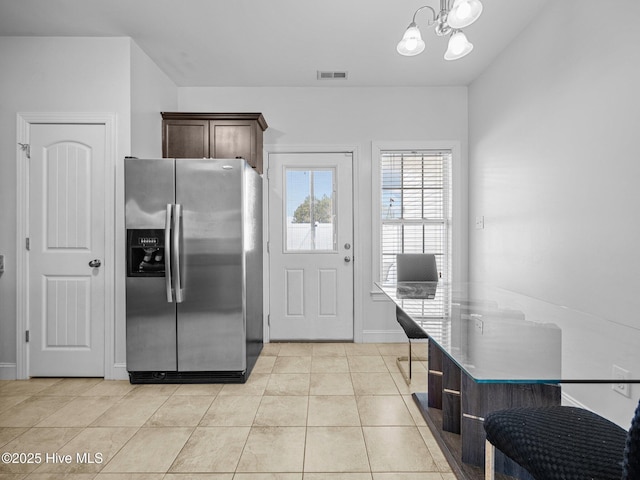 kitchen with pendant lighting, dark brown cabinetry, stainless steel fridge, a notable chandelier, and light tile patterned flooring