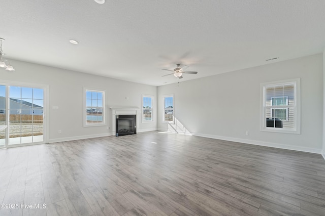 unfurnished living room featuring ceiling fan with notable chandelier, a mountain view, hardwood / wood-style floors, and a textured ceiling