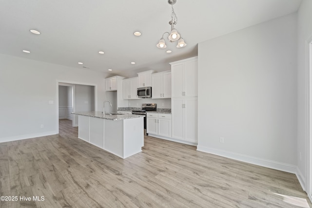 kitchen featuring white cabinetry, stainless steel appliances, a kitchen island with sink, and sink