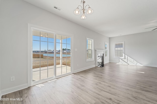 unfurnished living room with light hardwood / wood-style floors, a chandelier, and a water view