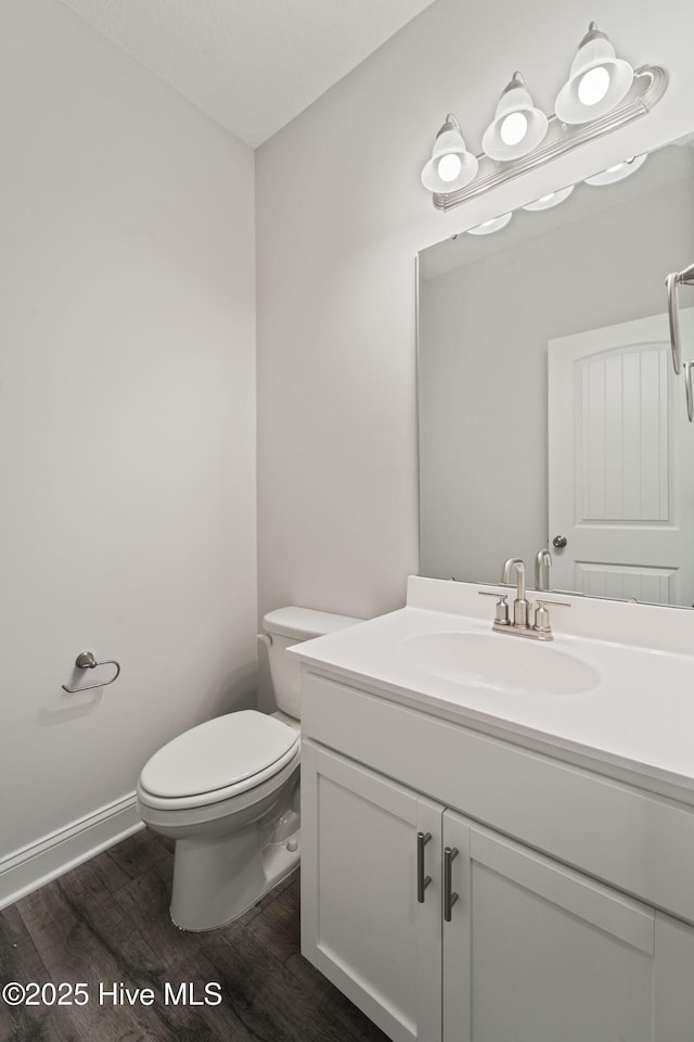 bathroom with wood-type flooring, toilet, and vanity