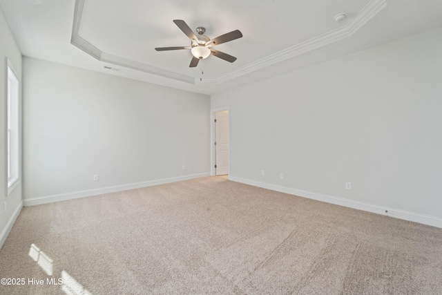 empty room featuring carpet floors, ornamental molding, a raised ceiling, and ceiling fan