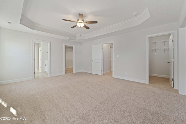 unfurnished bedroom with a tray ceiling, a walk in closet, and a closet