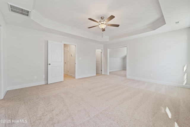 unfurnished bedroom featuring light carpet, crown molding, and a raised ceiling