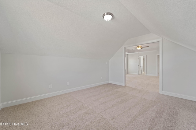 additional living space featuring vaulted ceiling, light carpet, and a textured ceiling