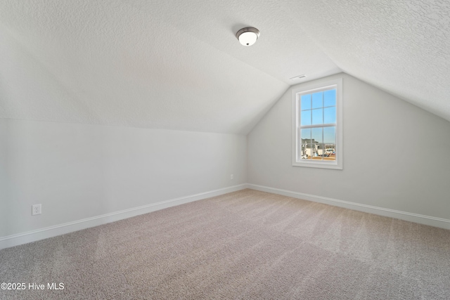 additional living space with lofted ceiling, carpet flooring, and a textured ceiling