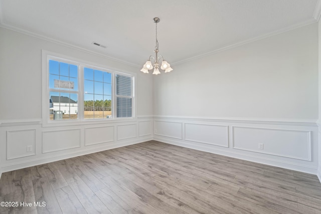 unfurnished room featuring crown molding, light wood-type flooring, and a notable chandelier