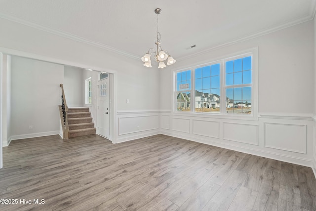 unfurnished dining area featuring hardwood / wood-style flooring, ornamental molding, and a chandelier