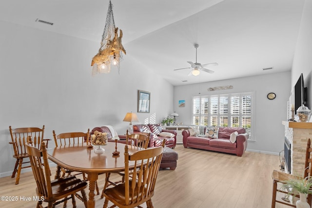 dining area with ceiling fan, light hardwood / wood-style flooring, and a fireplace