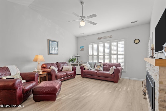 living room with a fireplace, ceiling fan, and light hardwood / wood-style floors