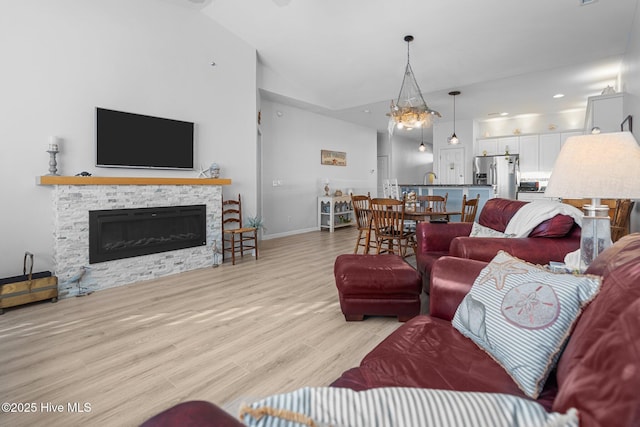 living room with a fireplace, vaulted ceiling, and light hardwood / wood-style flooring