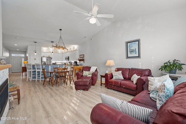 living room with ceiling fan, light hardwood / wood-style flooring, and vaulted ceiling