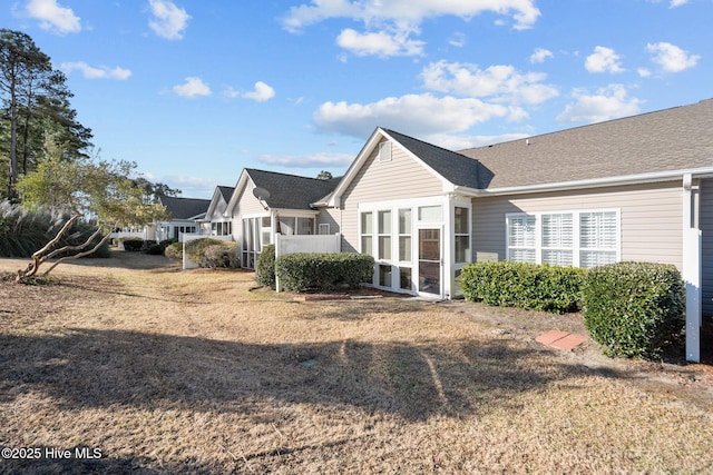 back of house with a lawn and a sunroom