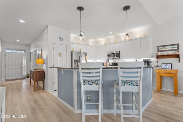 kitchen featuring white cabinets, a center island, appliances with stainless steel finishes, and hanging light fixtures