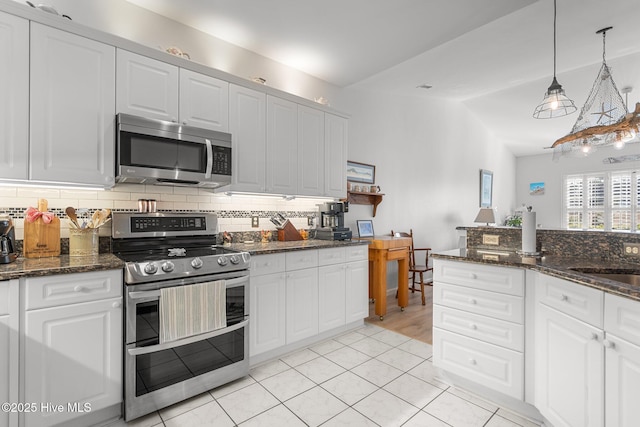 kitchen featuring stainless steel appliances, white cabinets, and vaulted ceiling