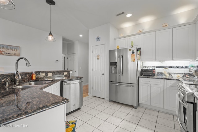 kitchen with appliances with stainless steel finishes, hanging light fixtures, white cabinetry, and sink