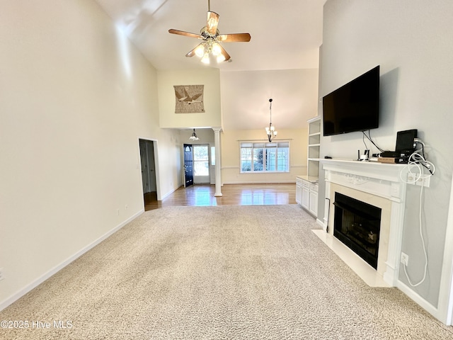 6104 Falcon Dr, New Bern, NC 28560 - unfurnished living room with ceiling fan, ornate columns, a fireplace with flush hearth, high vaulted ceiling, and light carpet