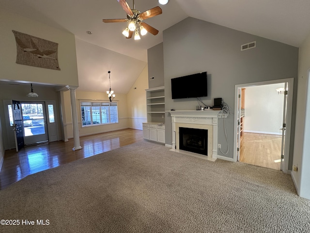 unfurnished living room featuring visible vents, a fireplace with flush hearth, carpet floors, ornate columns, and high vaulted ceiling