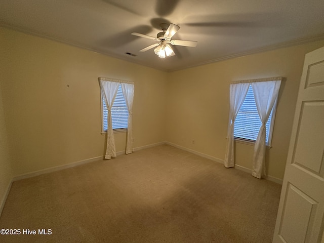 spare room with light carpet, baseboards, visible vents, a ceiling fan, and ornamental molding