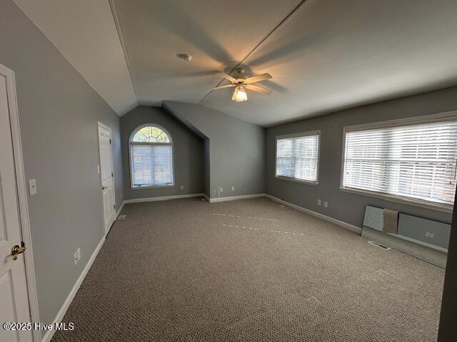 empty room with lofted ceiling, carpet floors, and baseboards