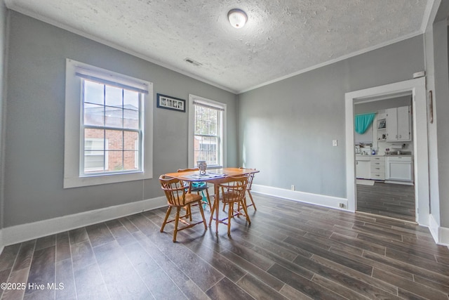 dining area with a textured ceiling, ornamental molding, and dark hardwood / wood-style floors