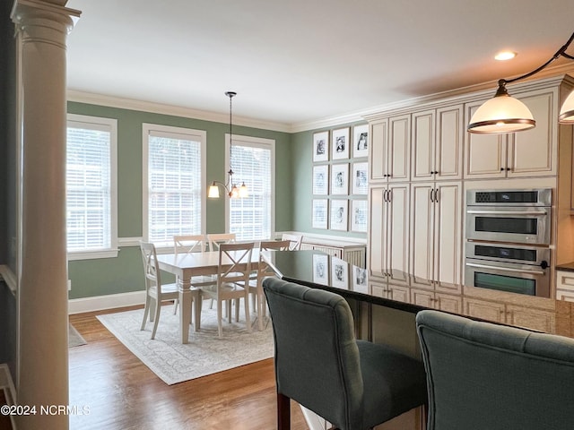 dining space featuring dark hardwood / wood-style flooring, decorative columns, crown molding, and a notable chandelier