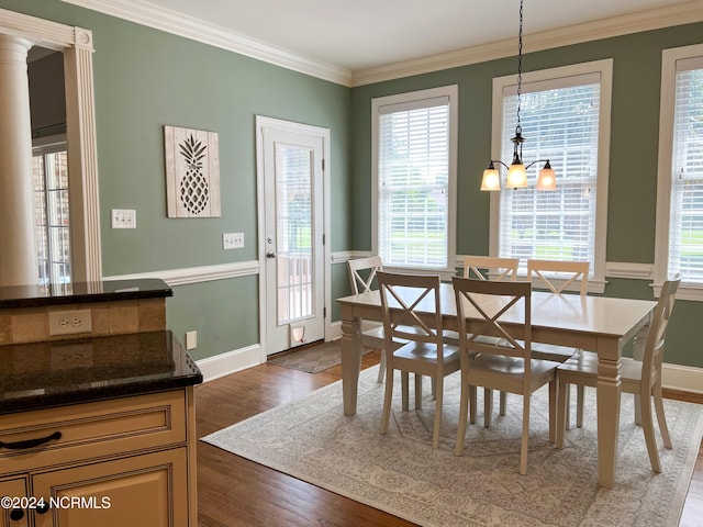 dining room featuring decorative columns, a chandelier, dark hardwood / wood-style floors, and ornamental molding