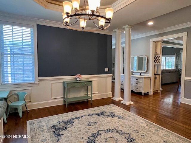 interior space with decorative columns, ornamental molding, a tray ceiling, a chandelier, and dark hardwood / wood-style floors