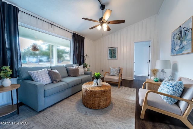 living room with ceiling fan, wood walls, vaulted ceiling, hardwood / wood-style flooring, and crown molding