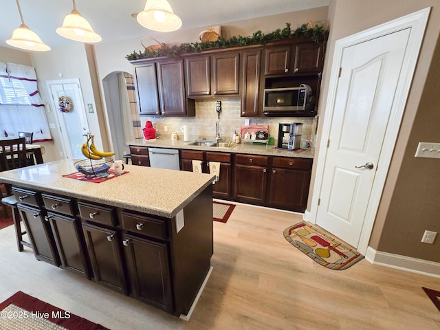 kitchen featuring pendant lighting, sink, appliances with stainless steel finishes, a center island, and dark brown cabinetry