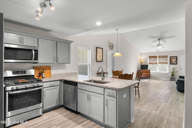 kitchen with vaulted ceiling, appliances with stainless steel finishes, gray cabinetry, and a sink
