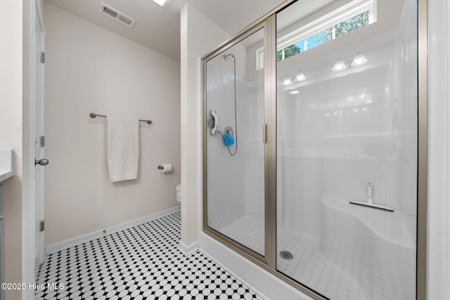 bathroom featuring tile patterned floors, toilet, visible vents, baseboards, and a shower stall