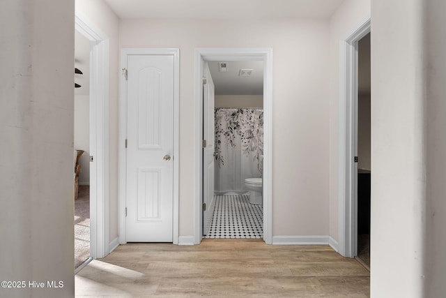 corridor with baseboards and wood finished floors